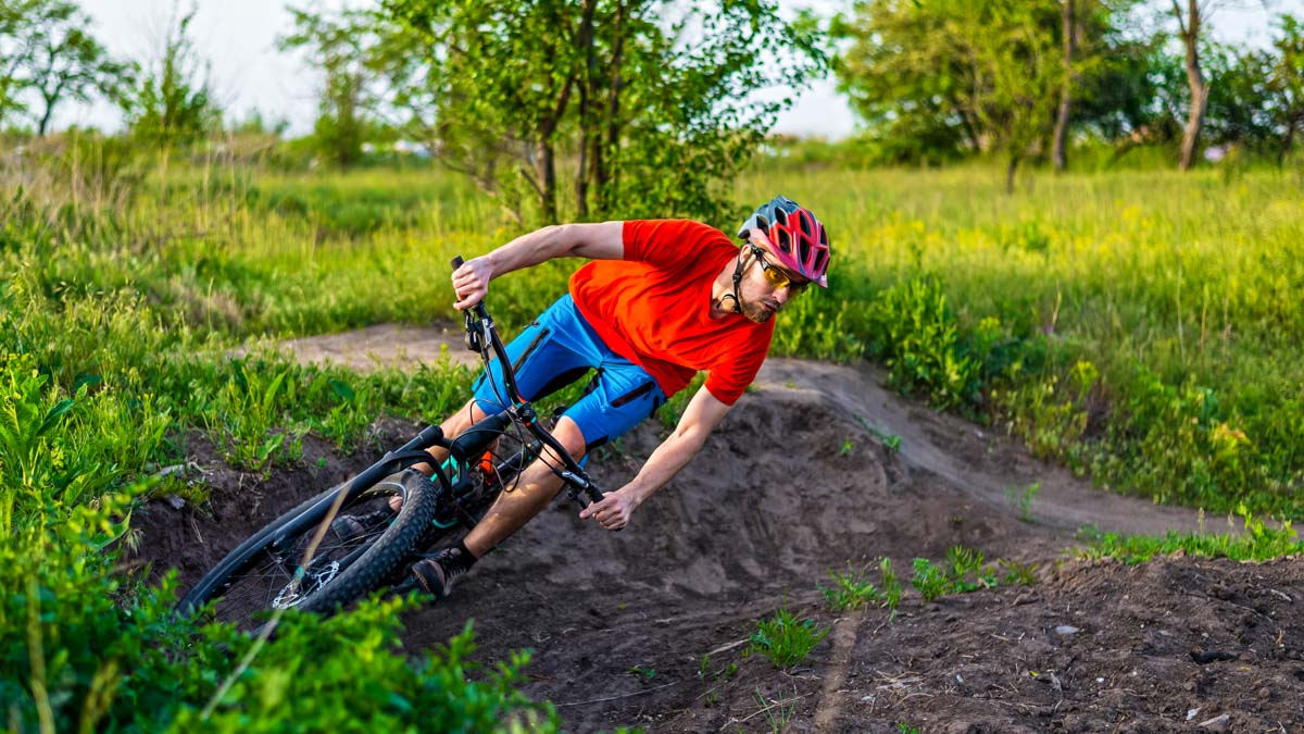 A Professional Cyclist In A Bright Orange T Shirt Rides Under A Switchback A Professional Cyclist In A Bright Orange T Shirt Rides Under A Switchback