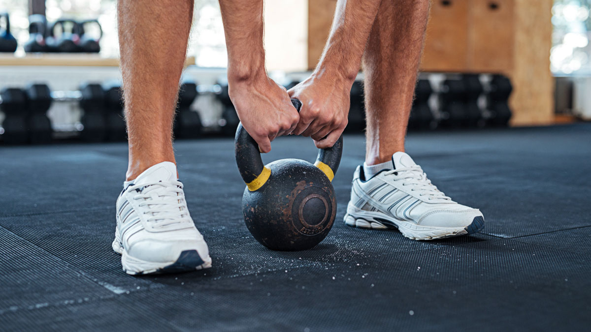 A Triathlete Holding A Kettleball Uses S&c Snacking To Get His Strength And Conditioning Workouts Done Athletic Male Legs In Gym, Man Holding Kettleball